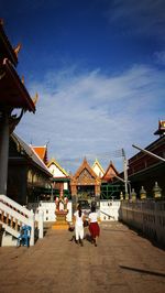 People walking by built structure against sky