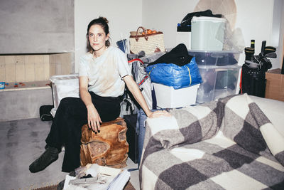 Portrait of woman sitting on wooden seat near boxes during relocation of house