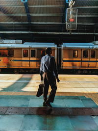 Full length rear view of man standing at railroad station