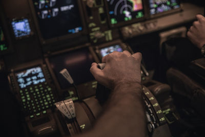 Cropped hand of pilot holding gear in airplane