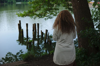 Rear view of woman standing against lake