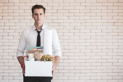 Portrait of young man standing against wall