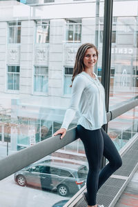 Portrait of smiling young woman against window