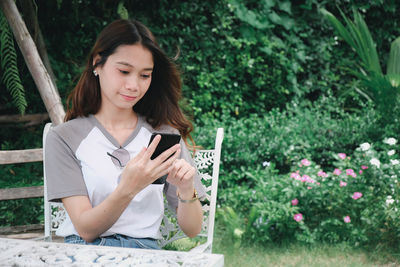Young woman using mobile phone while sitting outdoors