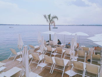 Chairs and tables on beach against sky