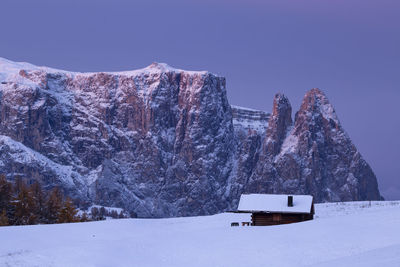 Snow covered land and mountains against clear sky