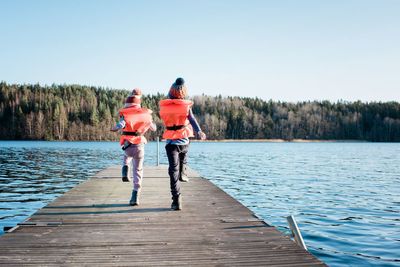 Brother and sister marching along a pier at the beach playing