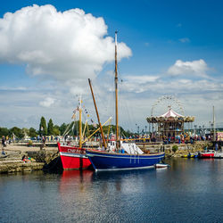 Sailboats moored at harbor against sky