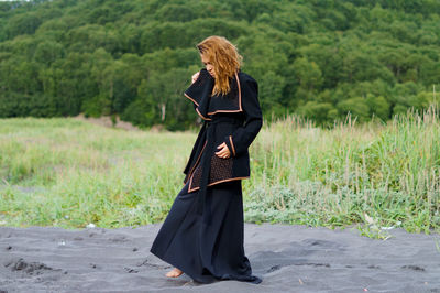 Mid adult woman wearing black dress at beach