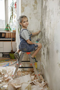 Full length of woman sitting against wall