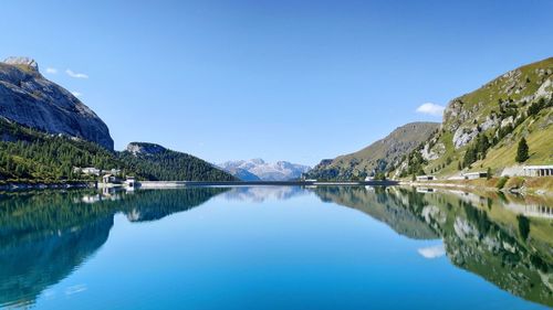 Scenic view of lake and mountains against clear blue sky