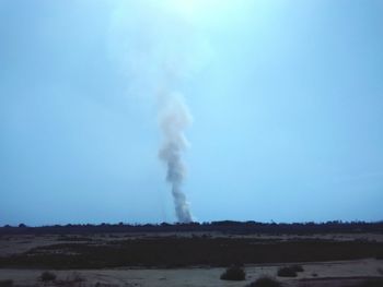 Low angle view of smoke emitting from land against clear sky