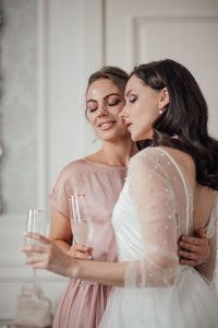 Bridesmaid and bride holding champagne flute