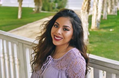 Portrait of cheerful young woman against railing