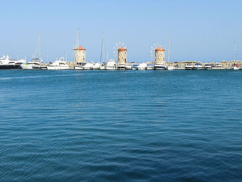 Sea by harbor against clear blue sky