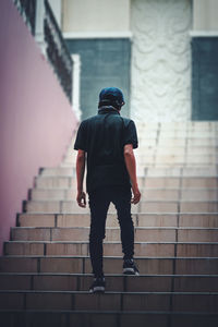 Rear view of man walking on staircase against building