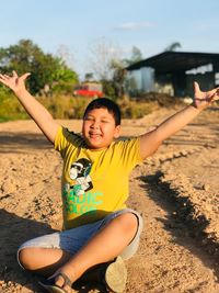 Portrait of happy girl playing at beach against sky