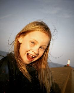 Portrait of cheerful girl against sea and sky during sunset