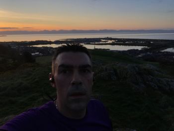 Portrait of man on landscape against sunset sky