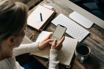 Unrecognizable business woman uses mobile phone and organizer for work.