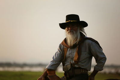 Man wearing hat standing on land against sky