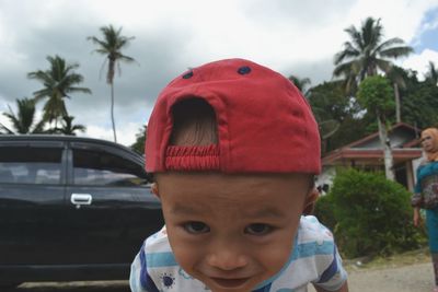 Close-up portrait of boy wearing red cap against car