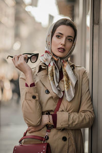 Fashionable woman standing by building in city