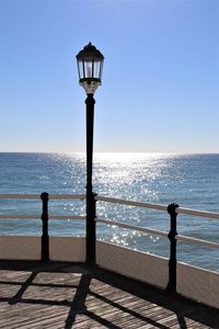 Street light by sea against clear sky
