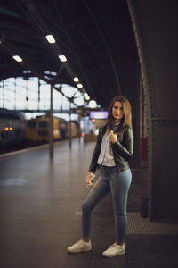 Portrait of young woman standing at railroad station platform