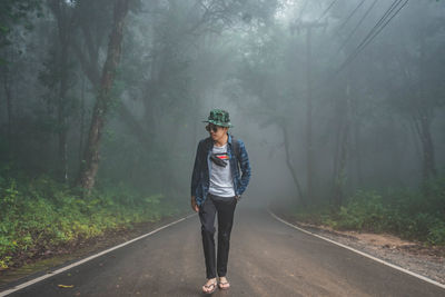 Man standing on road amidst trees in forest