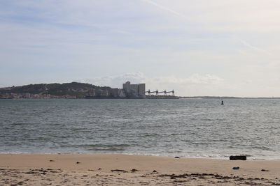 Scenic view of sea by buildings against sky