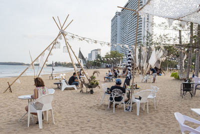 People sitting on table at beach against sky