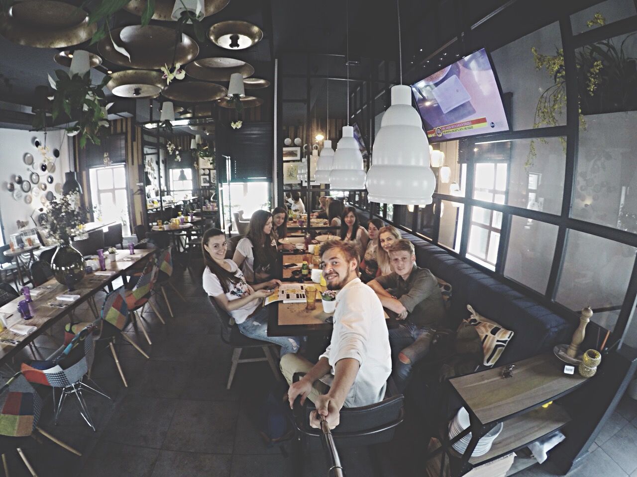 indoors, lifestyles, leisure activity, men, sitting, casual clothing, person, chair, high angle view, holding, table, standing, young adult, full length, large group of people, working, occupation, restaurant