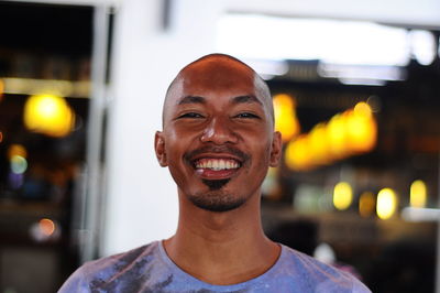 Portrait of smiling man against illuminated lighting equipment