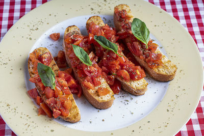 Savory tomato-based italian appetizers or bruschetta on toasted basil baguette slices.