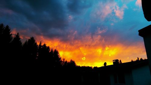 Low angle view of silhouette trees against cloudy sky