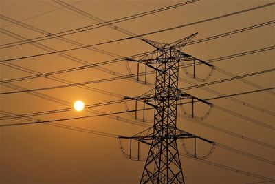 Low angle view of silhouette electricity pylon against sky during sunset