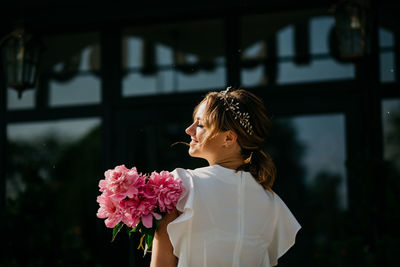 Rear view of woman standing by pink flowering plants