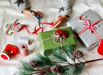 Cropped hand of woman cutting ribbon by christmas presents at table