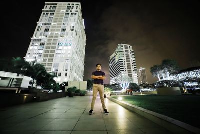 Full length of man against illuminated buildings in city at night