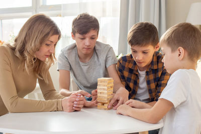A family, three boys and a woman, are enthusiastically playing a board game