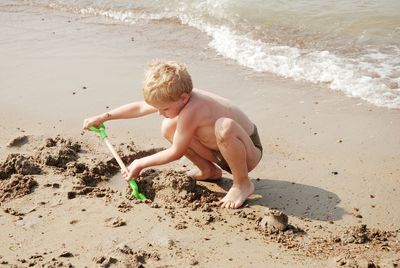 Full length of shirtless boy playing on shore at beach