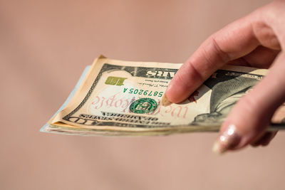 Close-up of hand holding paper against colored background