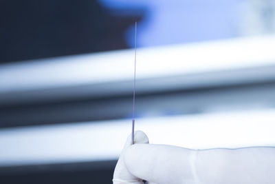 Cropped hand holding acupuncture needle in hospital