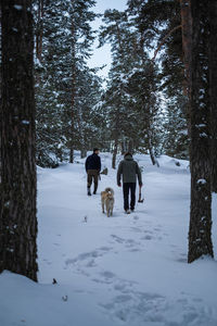 Rear view of man walking on snow covered landscape