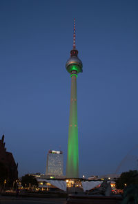 Illuminated fernsehturm against clear blue sky at dusk