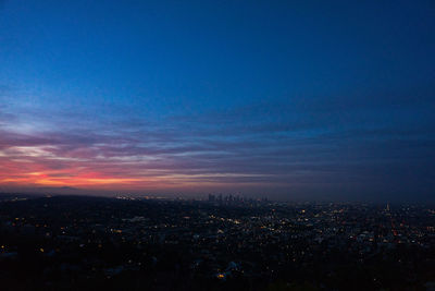 Aerial view of illuminated city against sky at sunset