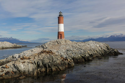 Lighthouse by sea against sky