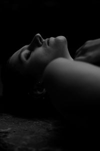 Close-up portrait of a woman lying in the dark