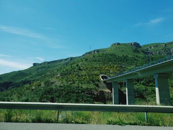 Bridge over mountain against sky